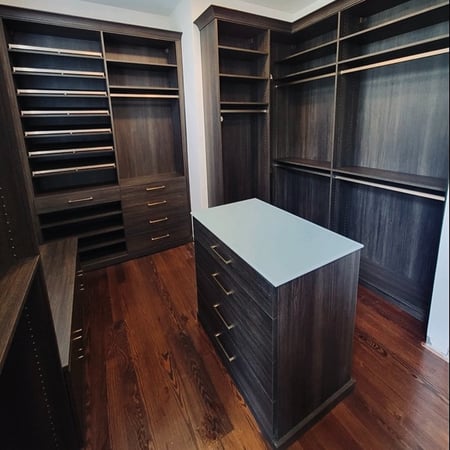 Dark brown walk-in closet organization with island California Closets New Orleans & Gulf Coast