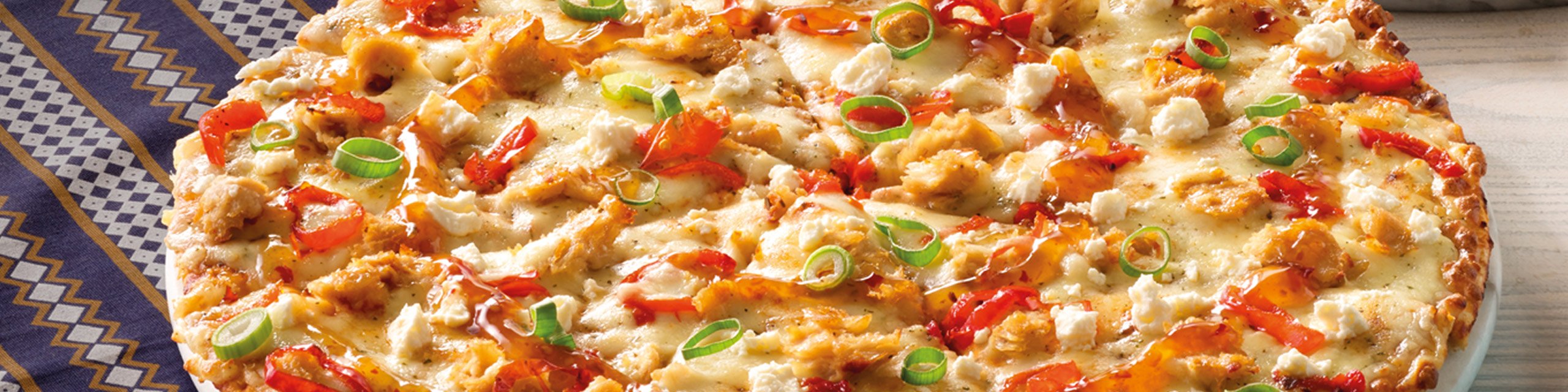 Large chicken pizza on a plate. Debonairs Pizza has affordable pizzas that you can order online for delivery.