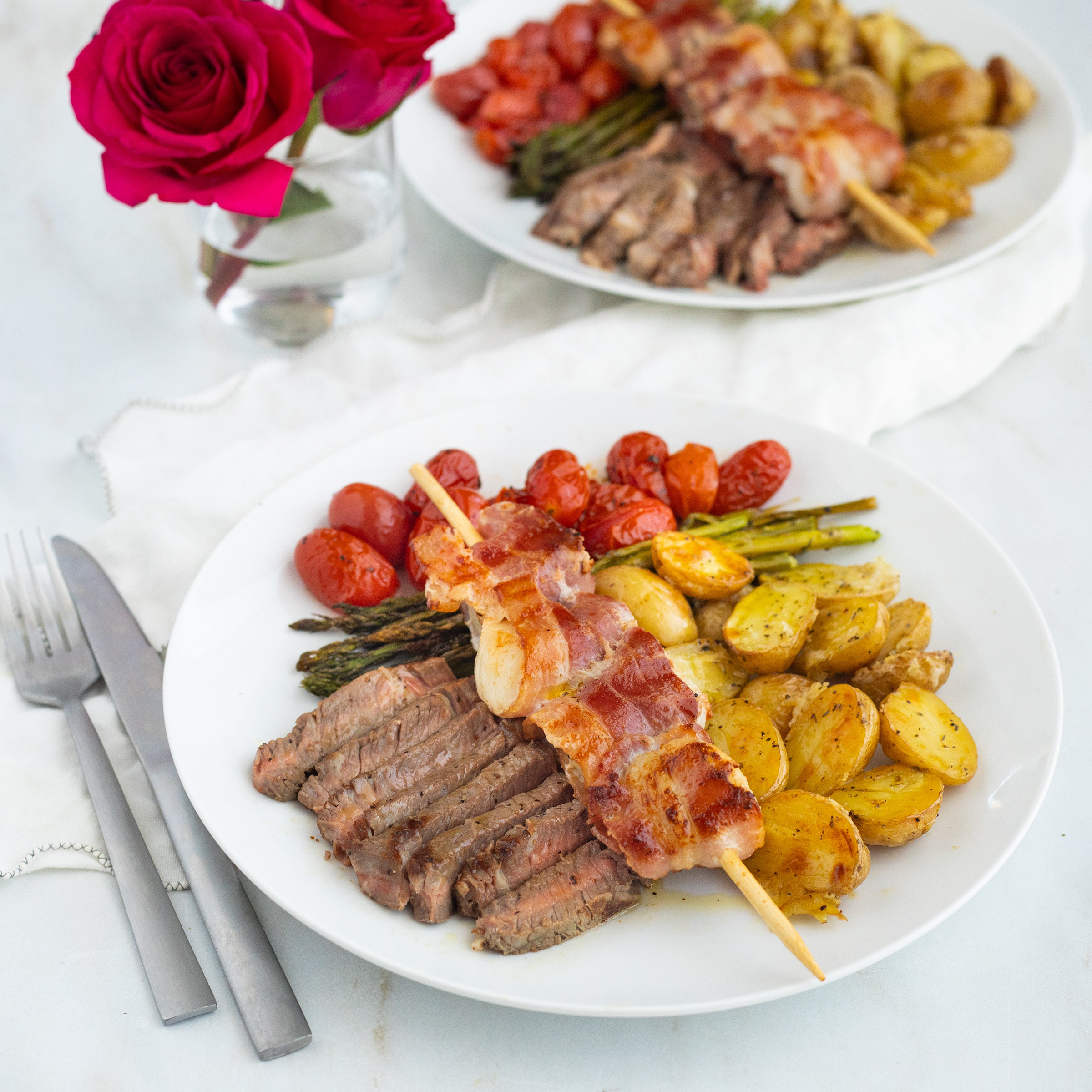 surf n turf ribeye with bacon wrapped scallops asparagus tomatoes and parmesan new potatoes