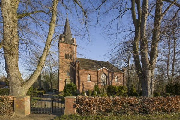 Das Kirchengebäude eingerahmt von Bäumen.
