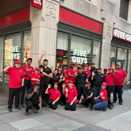 Crew members pose for a photograph outside the Five Guys restaurant at Metrotech Center in Brooklyn, New York.