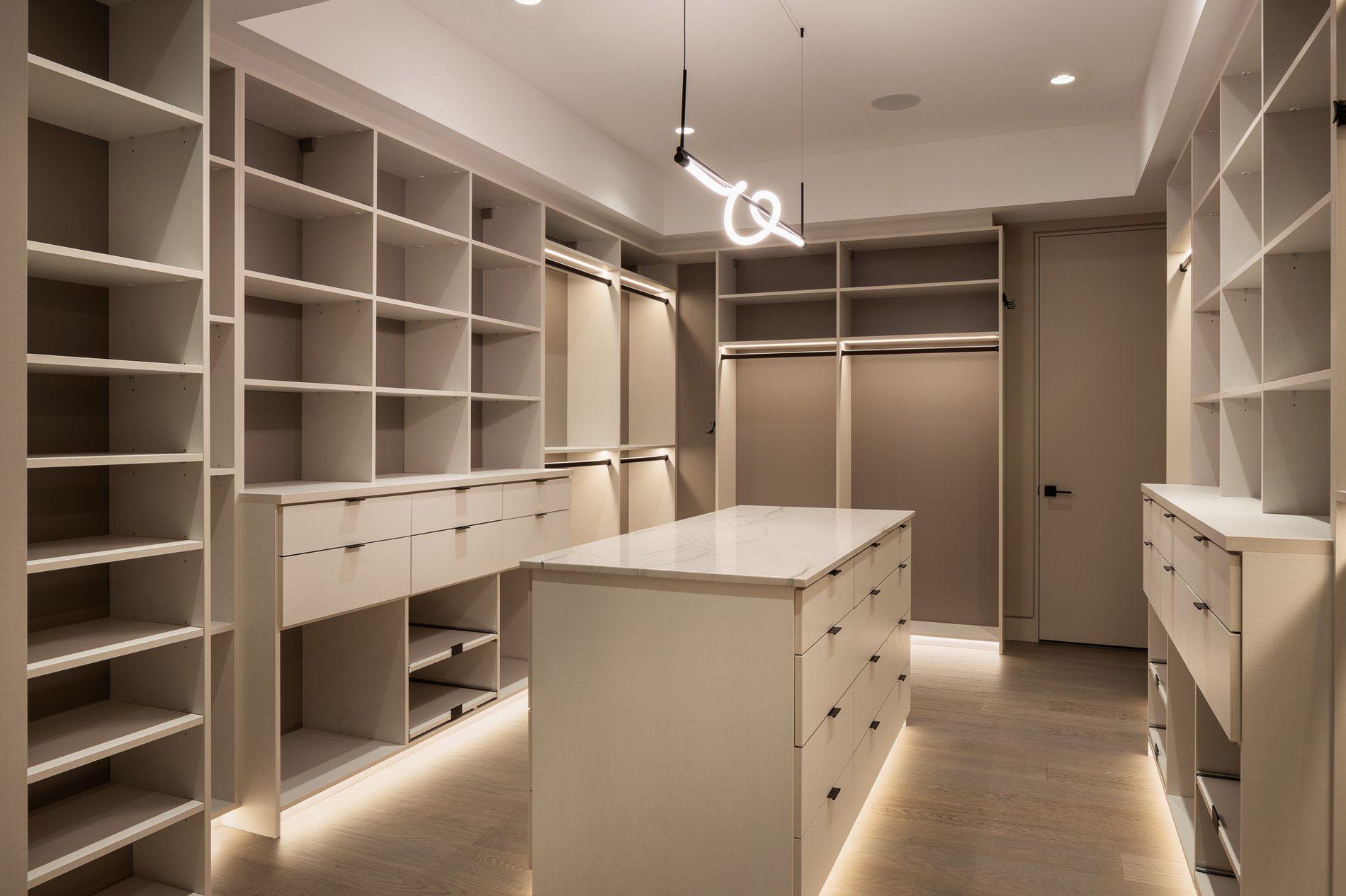 Large walk-in closet with shelving, drawers, center island and kick plate lights
