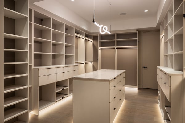 Large walk-in closet with shelving, drawers, center island and kick plate lights