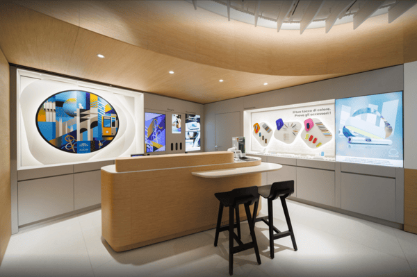 Immagine IQOS store con dispositivi a tabacco riscaldato su due tavoli di legno