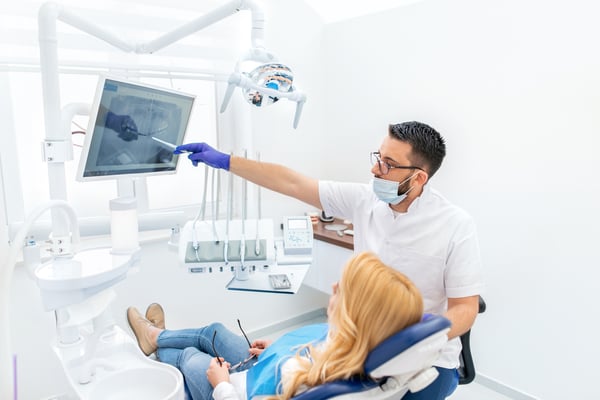 Patient in dentist chair reviewing X-rays with doctor
