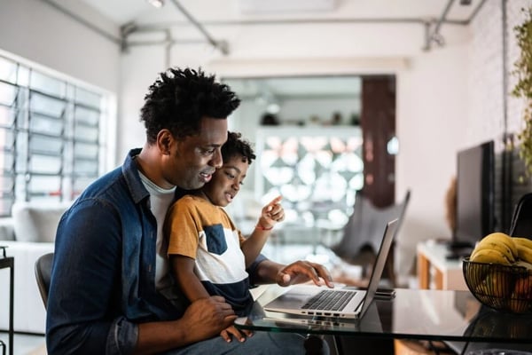 Padre e hijo usando una computadora portátil conectada a Internet por fibra óptica