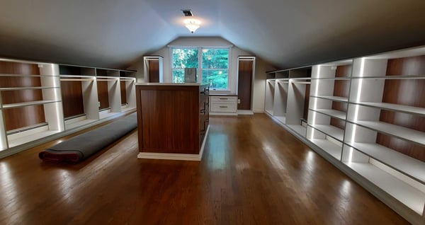 brown and white walk-in closet with sloped ceilings and center island with window