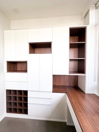 Office storage and desk with white cabinets and wood toned cubbies