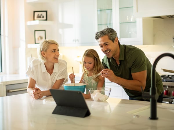 Familia en la cocina cocinando mientras miran un video de cocina en la computadora portátil