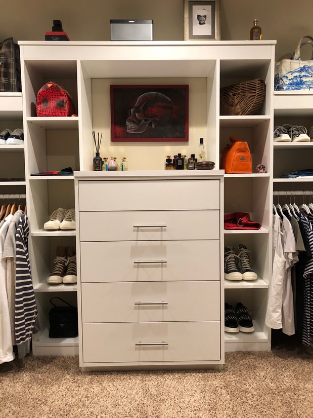 Off white walk-in closet with built-in dresser and shelves on each side