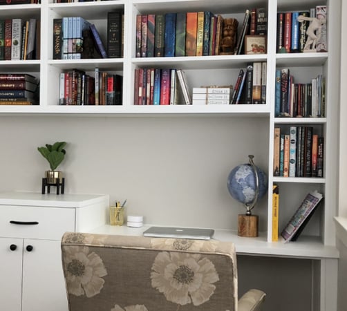 White bookshelves, desk and cabinets in home office setting