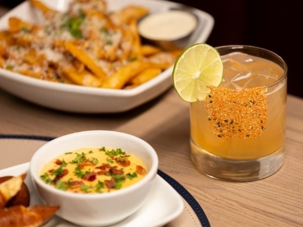 a table with pretzel bites, truffle parm fries and margaritas
