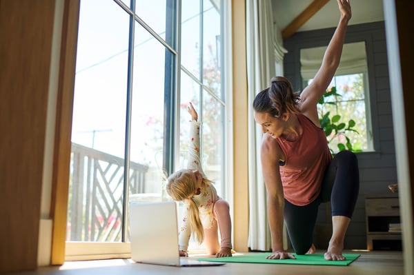 Madre e hija haciendo yoga juntas con una transmisión de video de un instructor de yoga