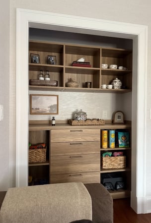 Warm wood toned reach-in pantry with countertop, drawers in center and shelves on both sides.