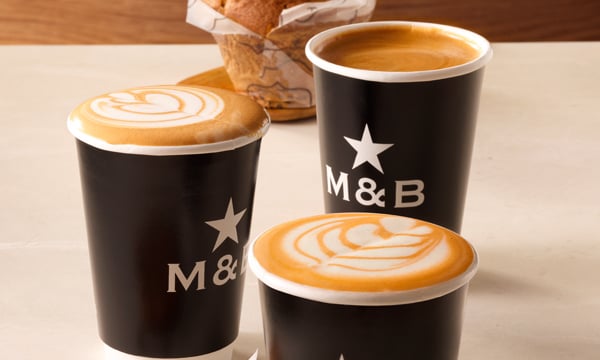 Range of takeaway coffee from Mugg & Bean including a cappuccino, latte and americano with a freshly baked muffin in the background.