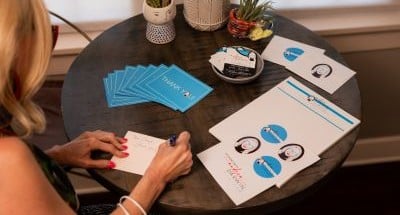 Customer writing thank-you notes alongside printed marketing flyers and custom stationery from FedEx Office.