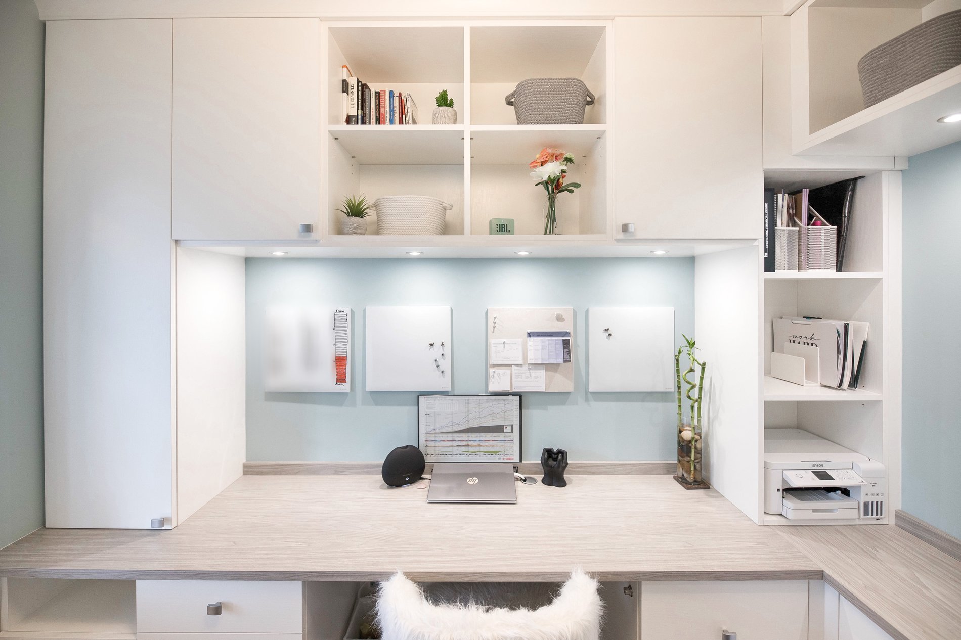 Front view of desktop, cupboard and cubby space in office with recessed lighting