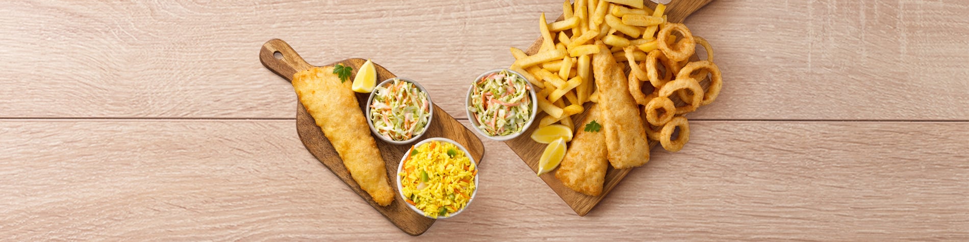 Seafood platter deal from Fishaways showing a Hake, Rice & Coleslaw meal and a Hake, Chips, Coleslaw & Onion Rings Platter on a wood background