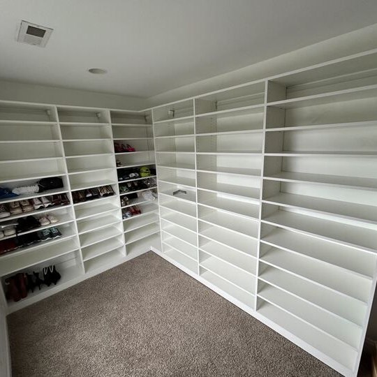 Greensboro - Custom closets - cornered white custom shelving system in a walk-in closet with a minimalist layout