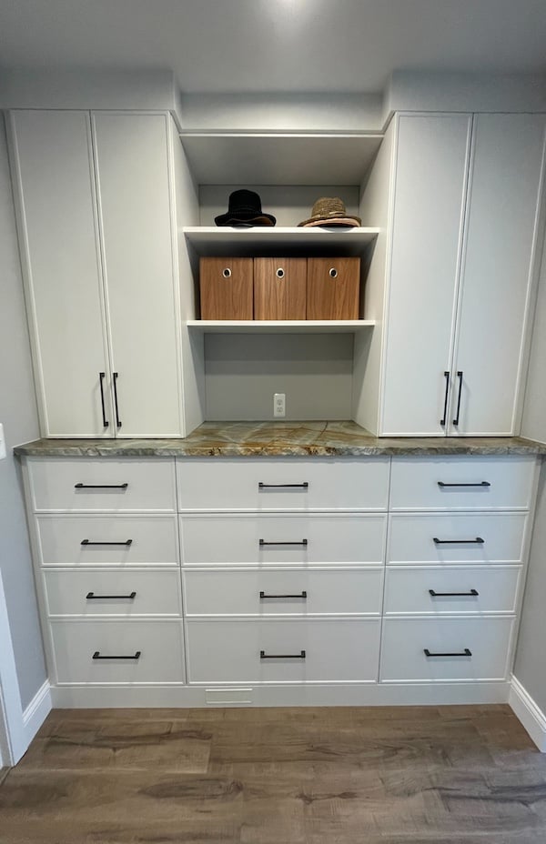 White custom storage with drawers, tall cabinets, open shelving, and a stone countertop