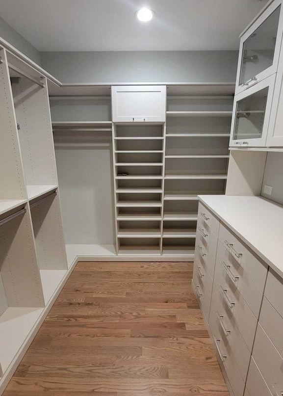 A large walk-in closet with extensive shelving, dividers, drawers, and a countertop workspace.