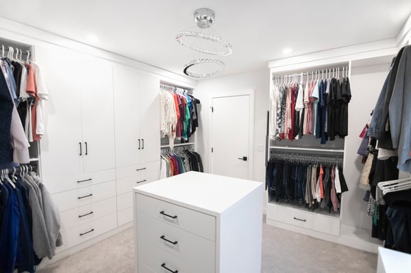 White walk in closet with floor to ceiling storage. Closed cabinetry and island provides plenty of concealed storage. Add black hardware for a contrasting element.
