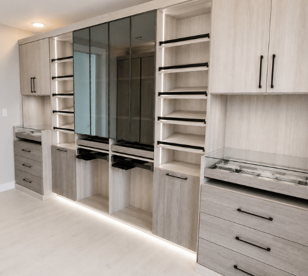Custom boutique-style wardrobe in Boca Raton, FL with integrated lighting, slanted display shelves, jewelry organizer, and black shadowbox glass doors by California Closets