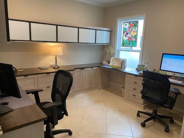A wrap-around double desk with drawers and floating cabinets overhead.