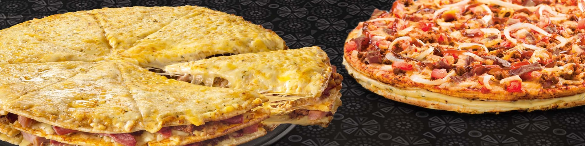 Two large pizzas on a grill placed on a wooden table