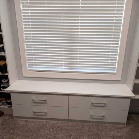 A white window seat with built-in drawers beneath for additional space.
