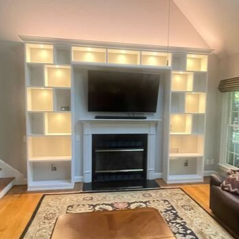 Virginia Beach - Custom entertainment center - Custom built-in media wall with illuminated shelving surrounding a fireplace and TV.