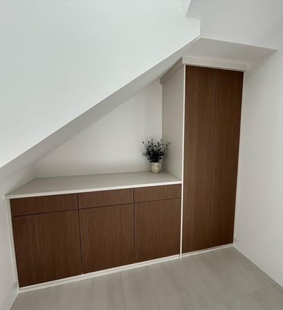 Custom under-stair built-in with warm wood cabinetry, concealed storage, countertop surface, and tall cabinet.