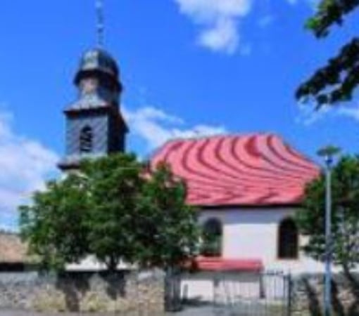 Außenansicht der Evangelischen Kirche Dolgesheim vor blauem Himmel.