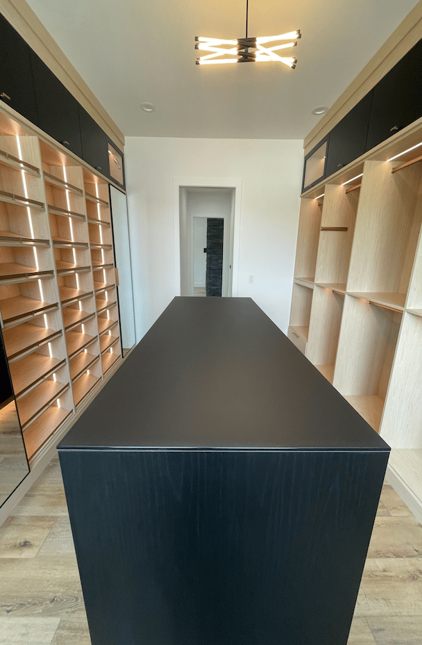 two tone luxe walk-in closet with center island and integrated lighting
