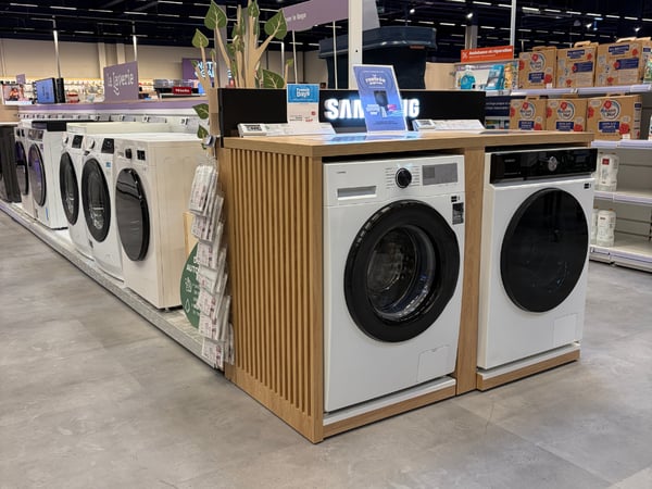 Vue du rayon lave linge avec les produits disposés en magasin.