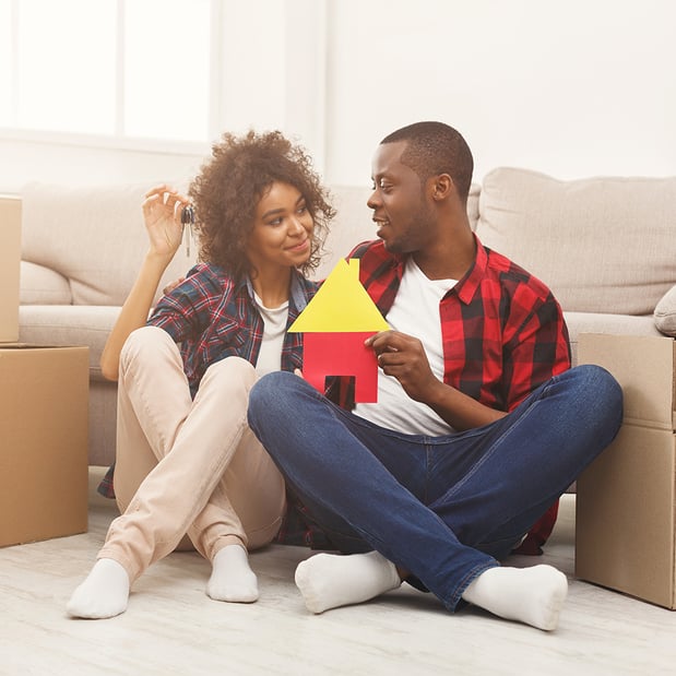 A woman and a man sitting on the floor in front of a couch