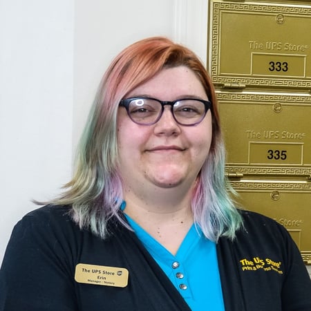 Smiling female associate standing in front of mailboxes in The UPS Store