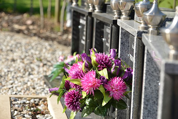 A row of cremation memorials, with a floral tribute laid before them