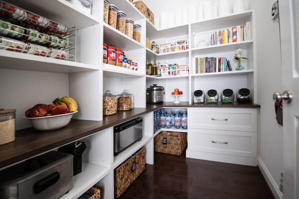 Custom pantry with contrasting, dark wood countertop and storage bins.