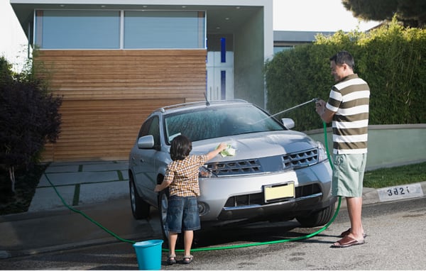 Father and son washing car in driveway