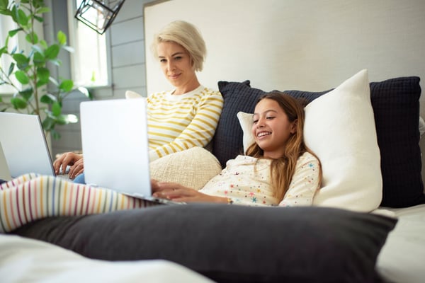 Mother and daughter both with laptops using internet