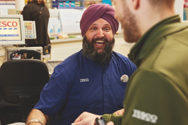 Tesco worker smiling as he works on the till