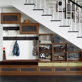 Custom brown cabinets for storage below a white staircase by California Closets Philadelphia, Pennsylvania.