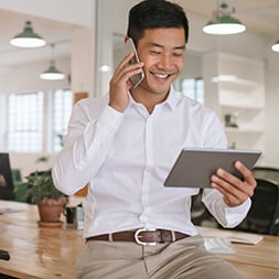 Man talking on phone and looking at tablet.