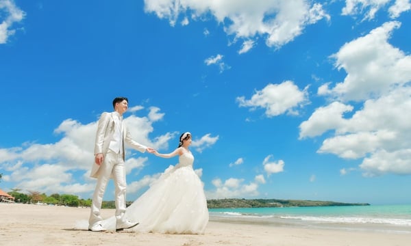 ビーチで手をつないだ結婚式衣装の新郎新婦