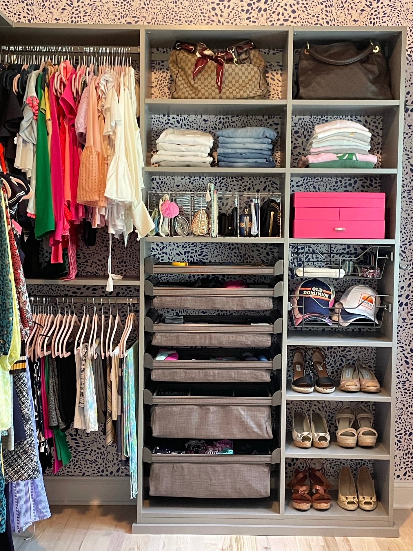 grey closet filled with clothing and baskets with animal print wallpaper