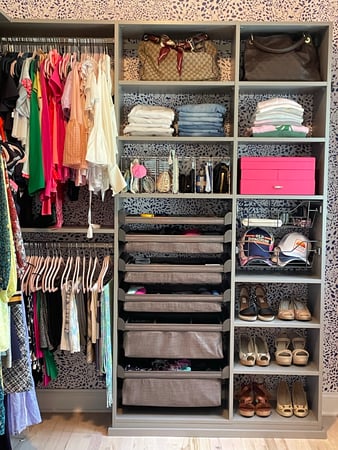 grey closet filled with clothing and baskets with animal print wallpaper