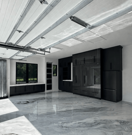 Custom garage storage with black floor-to-ceiling cabinets, built-in refrigerator, countertop, and enclosed storage.