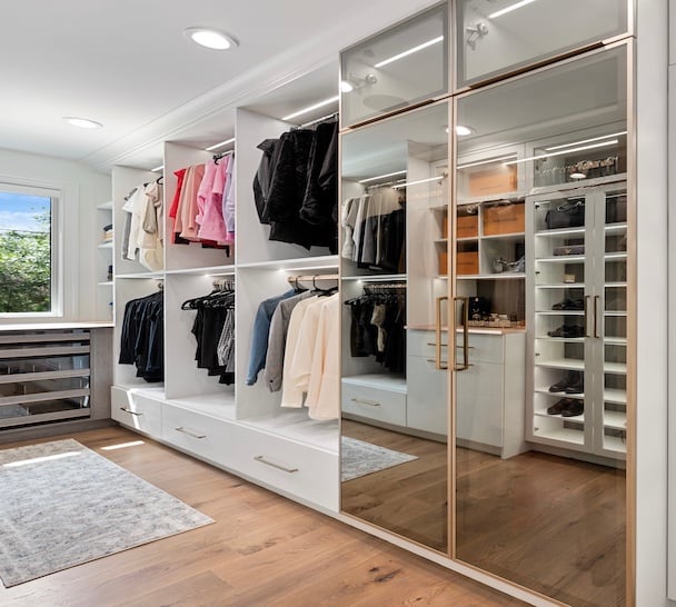 Walk in closet design with custom closets, closet organizers, closet cabinets, shoe storage, and mirrored wardrobe doors in Dearborn, Michigan by California Closets Greater Detroit