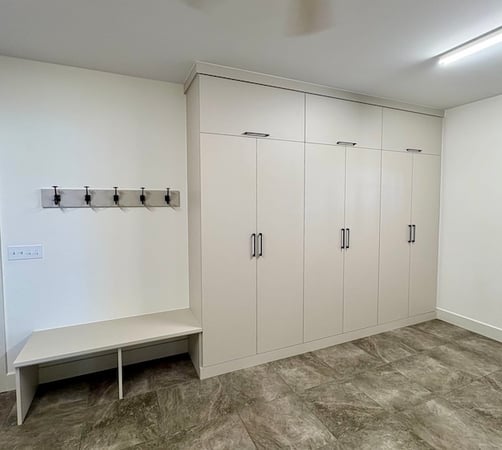 White custom mudroom cabinets with built-in bench and hooks for organized entryway storage and home organization in Indian River, Michigan